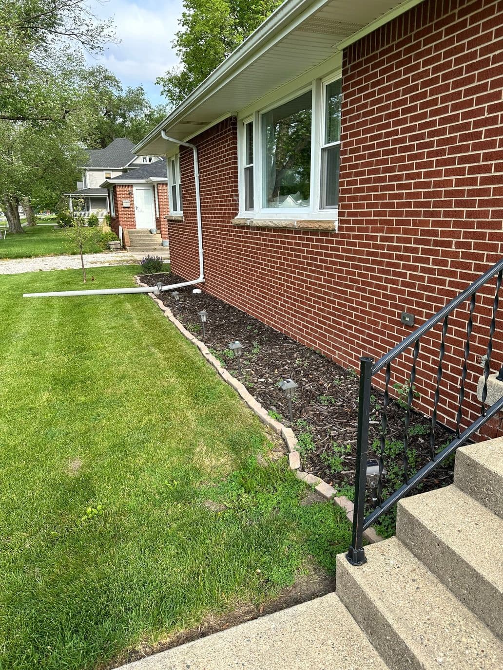 Well-maintained brick home with landscaped garden and steps leading to the entrance.